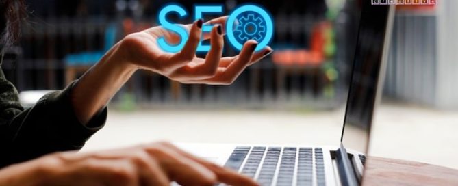 hands holding "SEO" while typing on a laptop